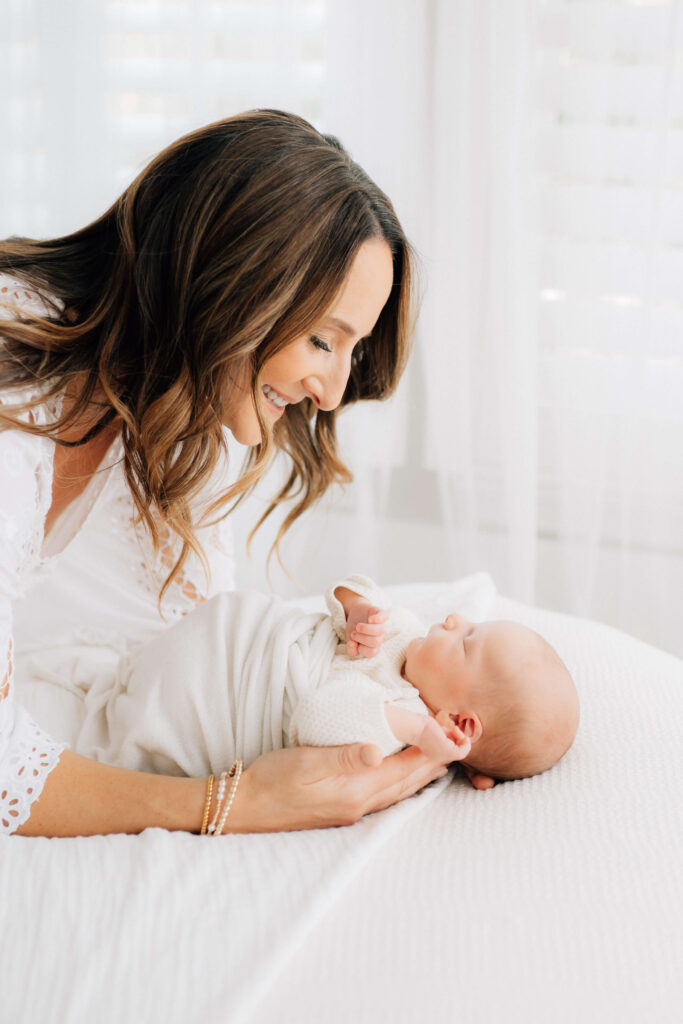 Denver newborn photographer session with mom looking down at baby on white blankets
