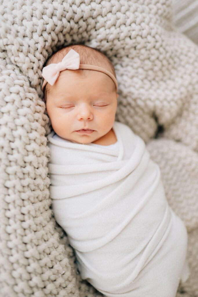 newborn baby session wrapped in a swaddle lying in a chunky knit blanket