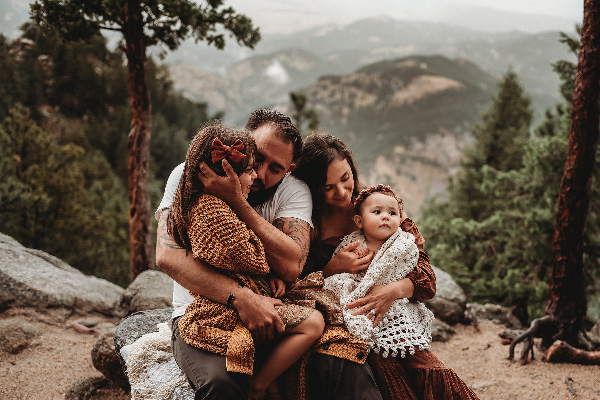 Family of four snuggled on top of a mountain