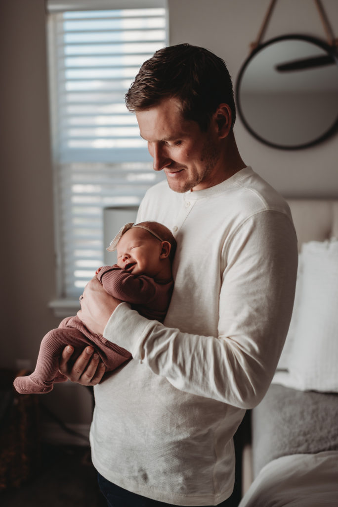 dad holding newborn baby against his chest