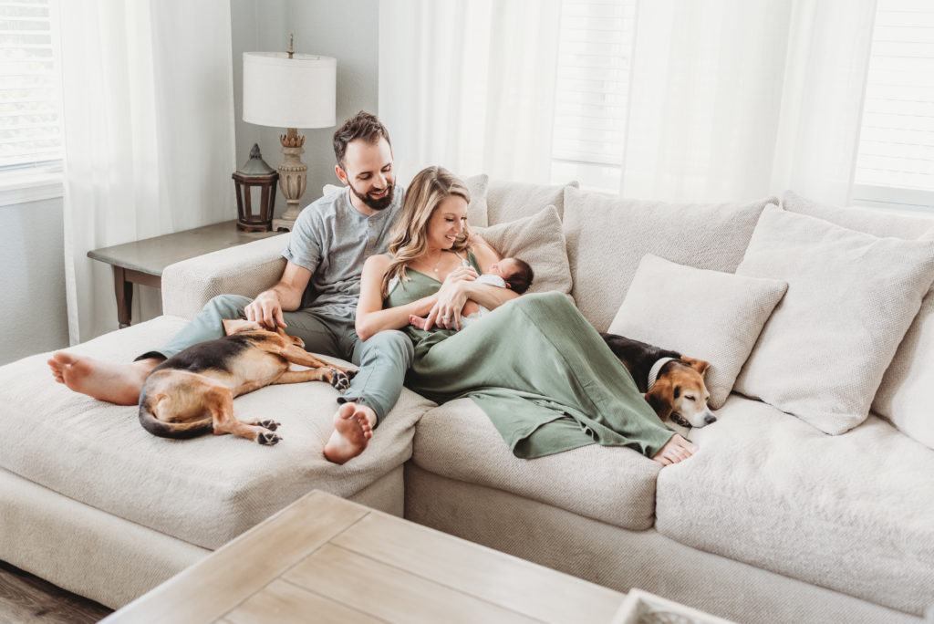 New parents with baby and two dogs on couch 