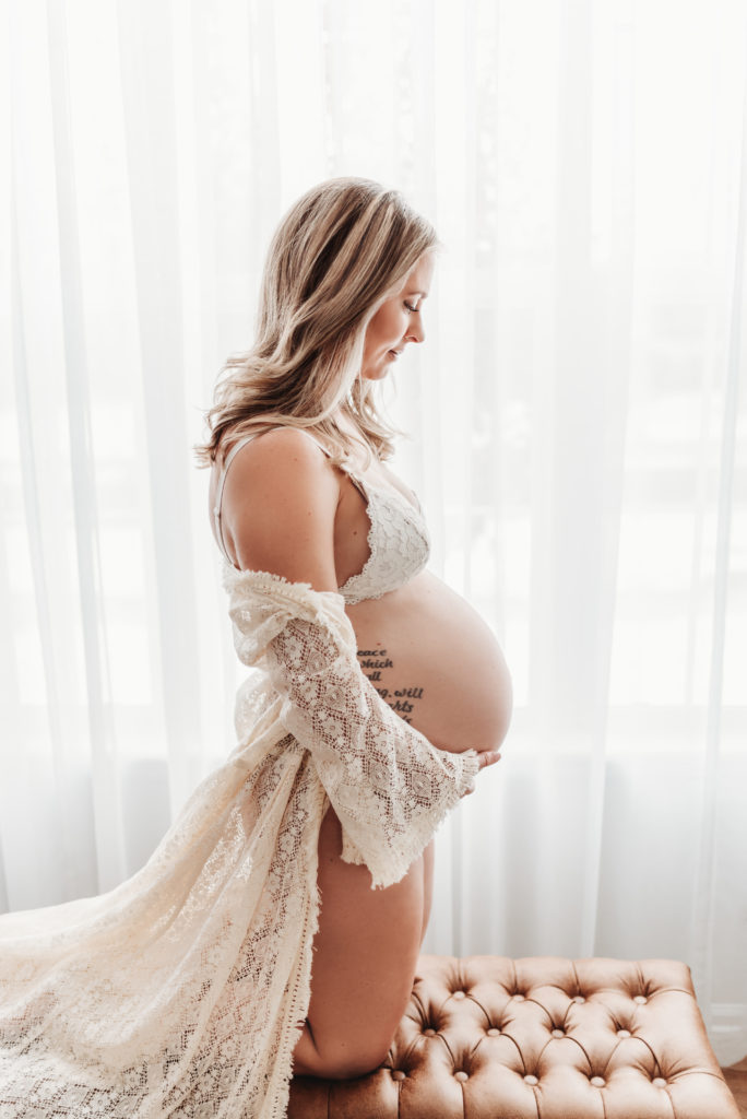 Expecting mother in lace robe and bra holding her belly