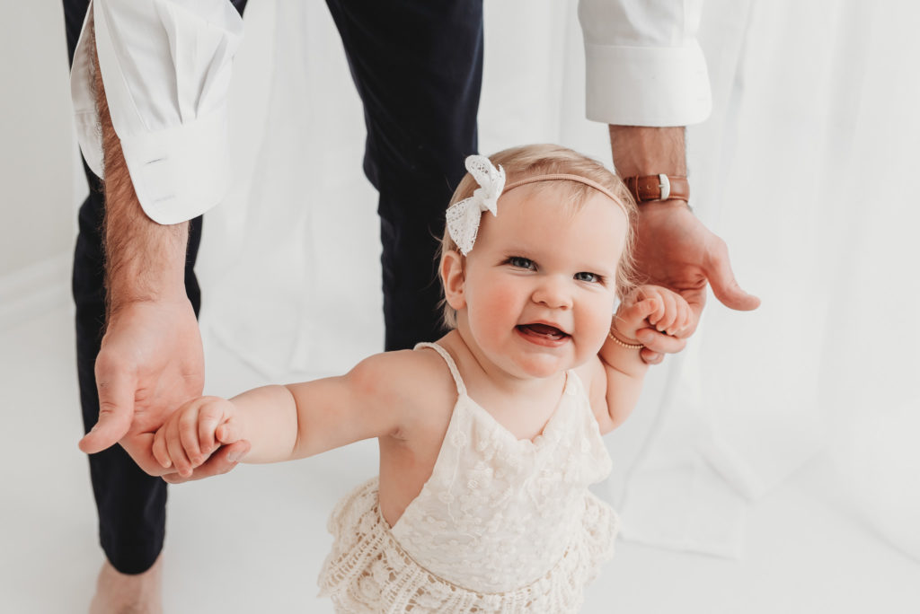 Baby is having fun with dad during her first birthday studio milestone session