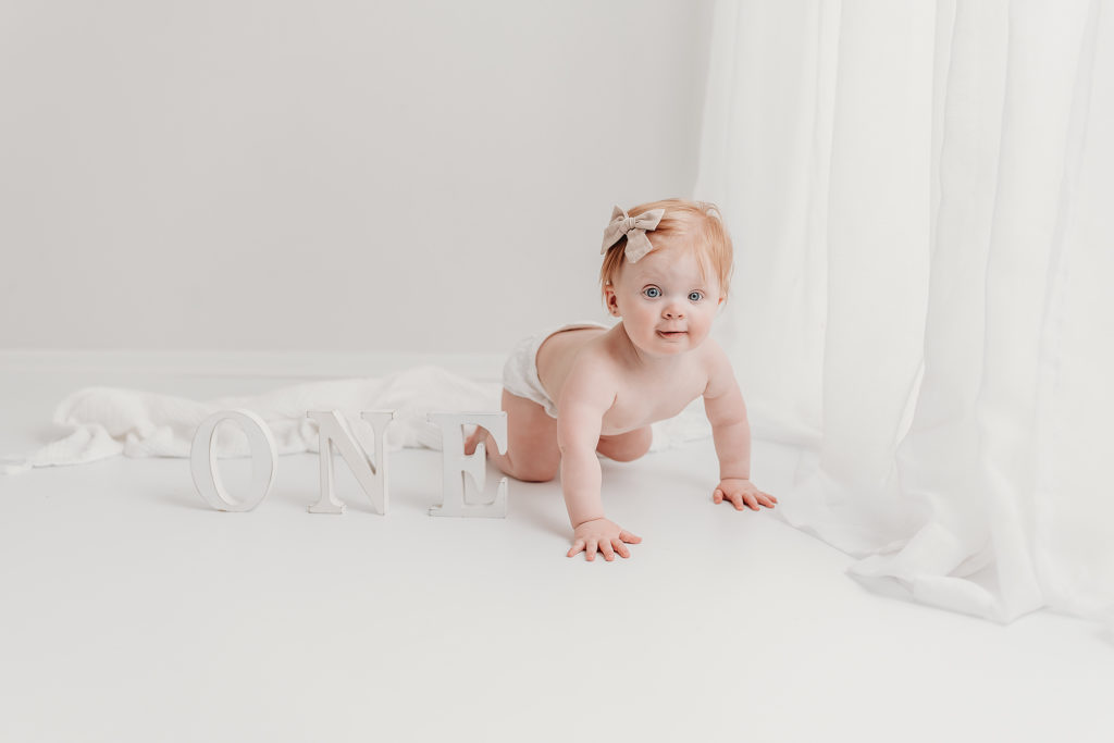 one year old baby crawling on a white studio floor