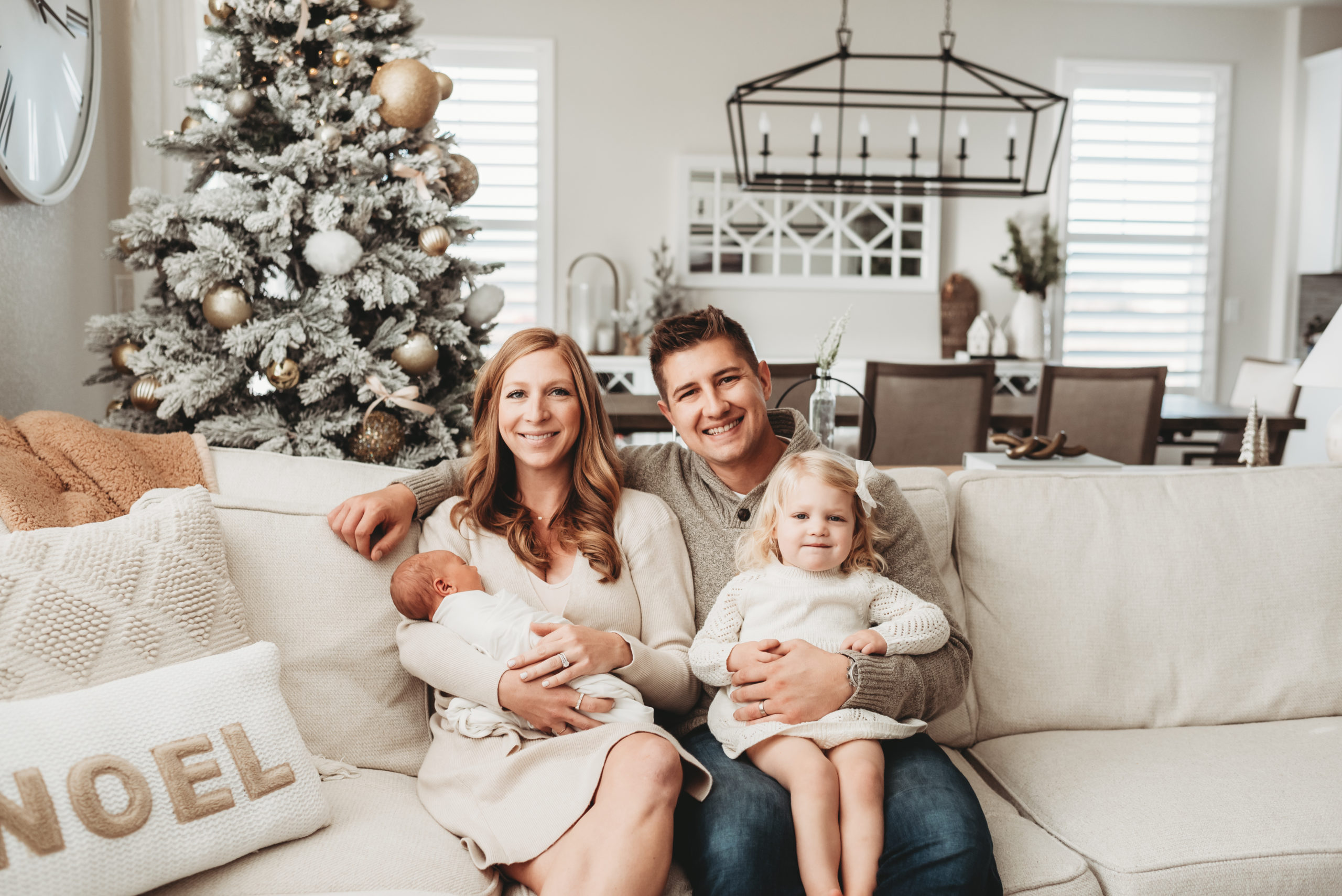 family snuggled on the couch in front of their christmas tree during lifestyle newborn photos