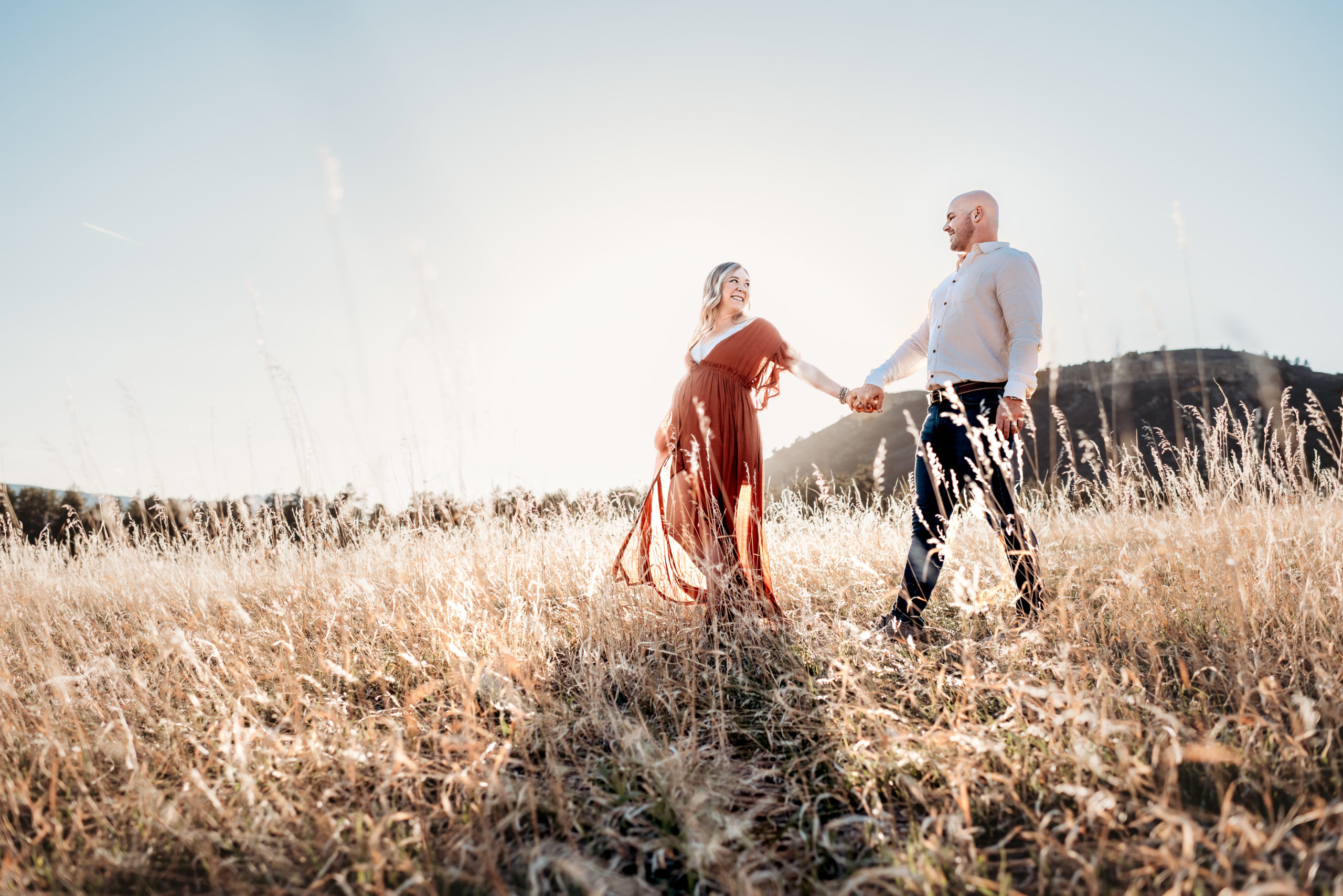 husband and wife walking in field expecting baby