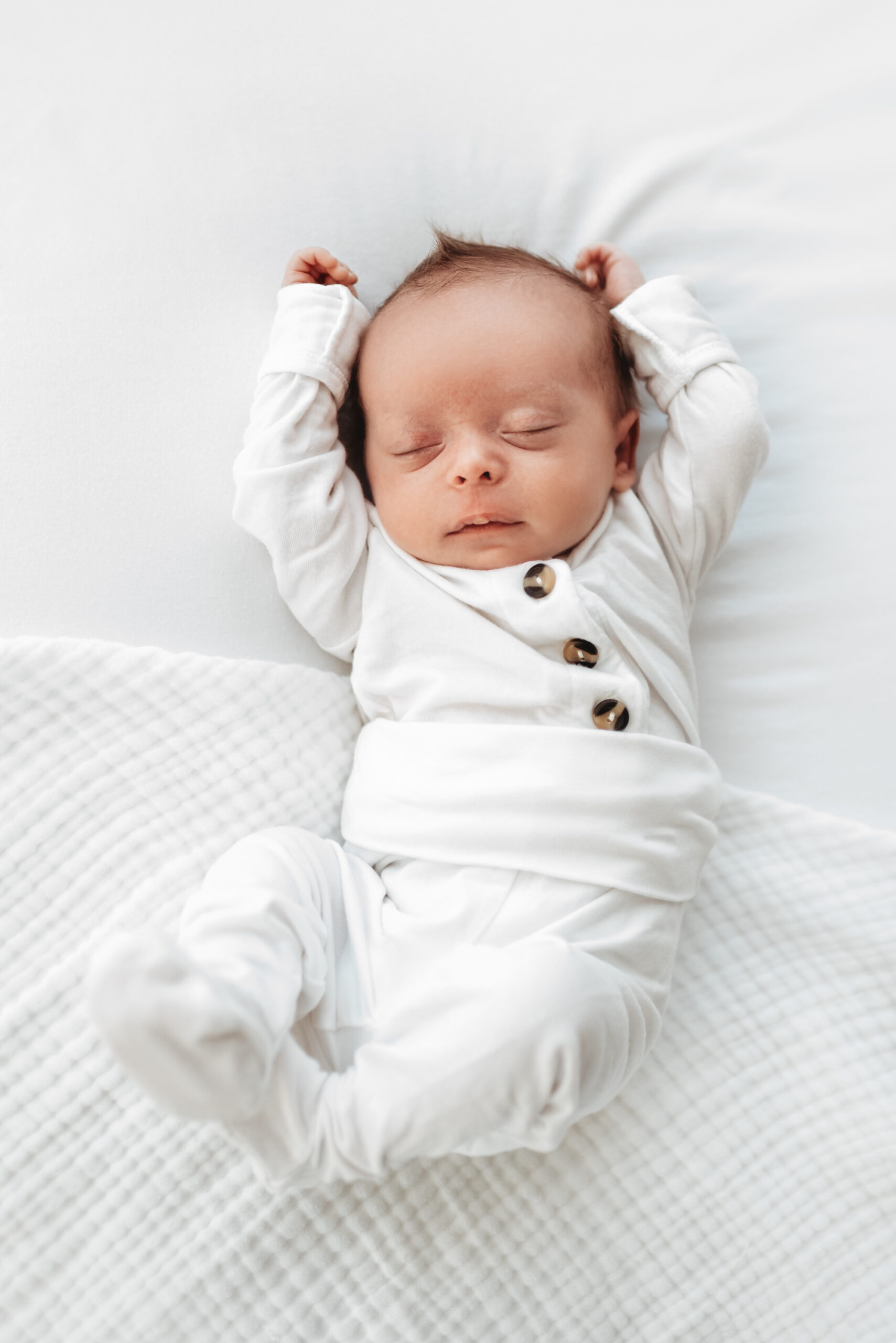 rocky mountain sleeping baby stretching arms on bed