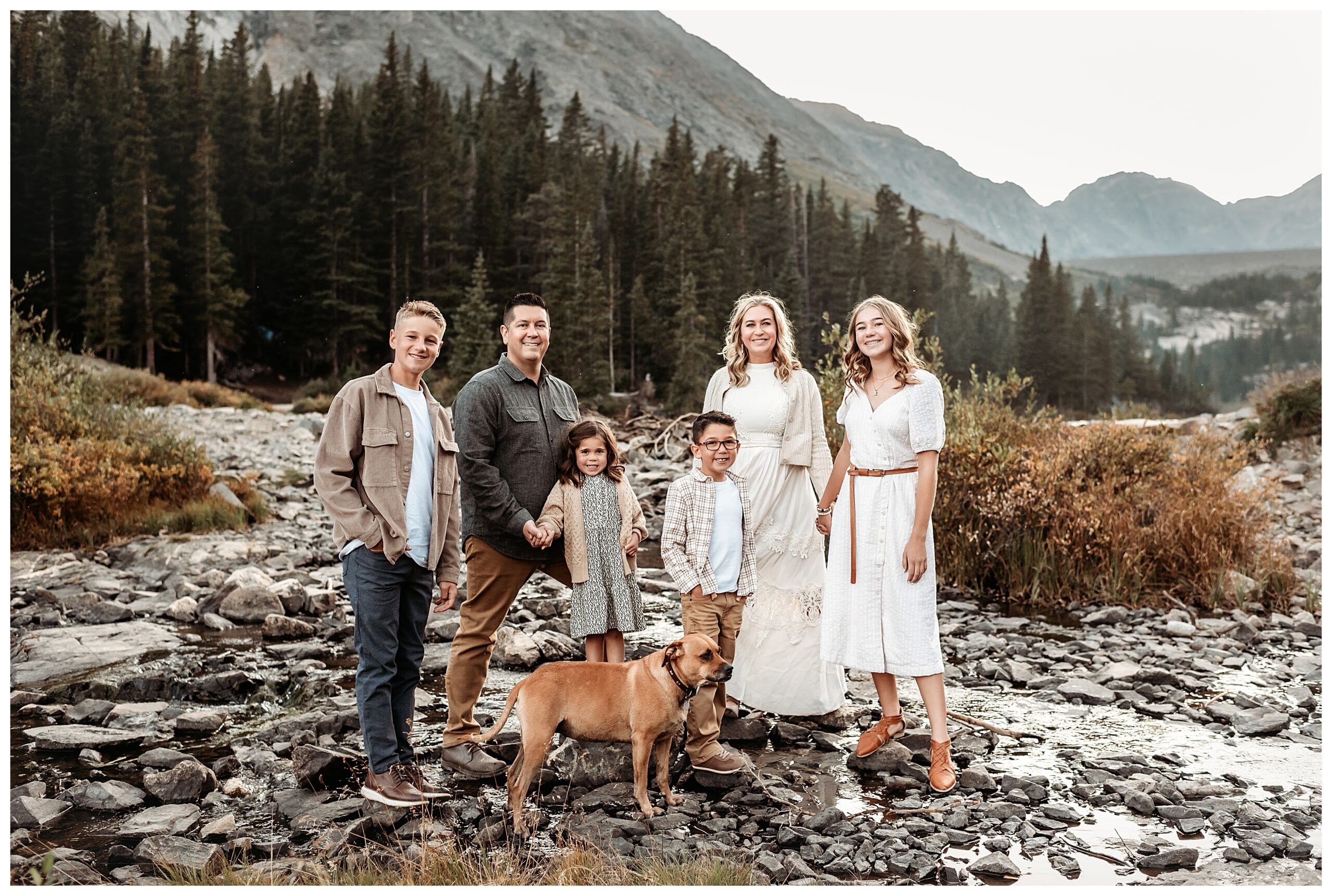 family of six standing in front of blue lakes breckenridge with their dog