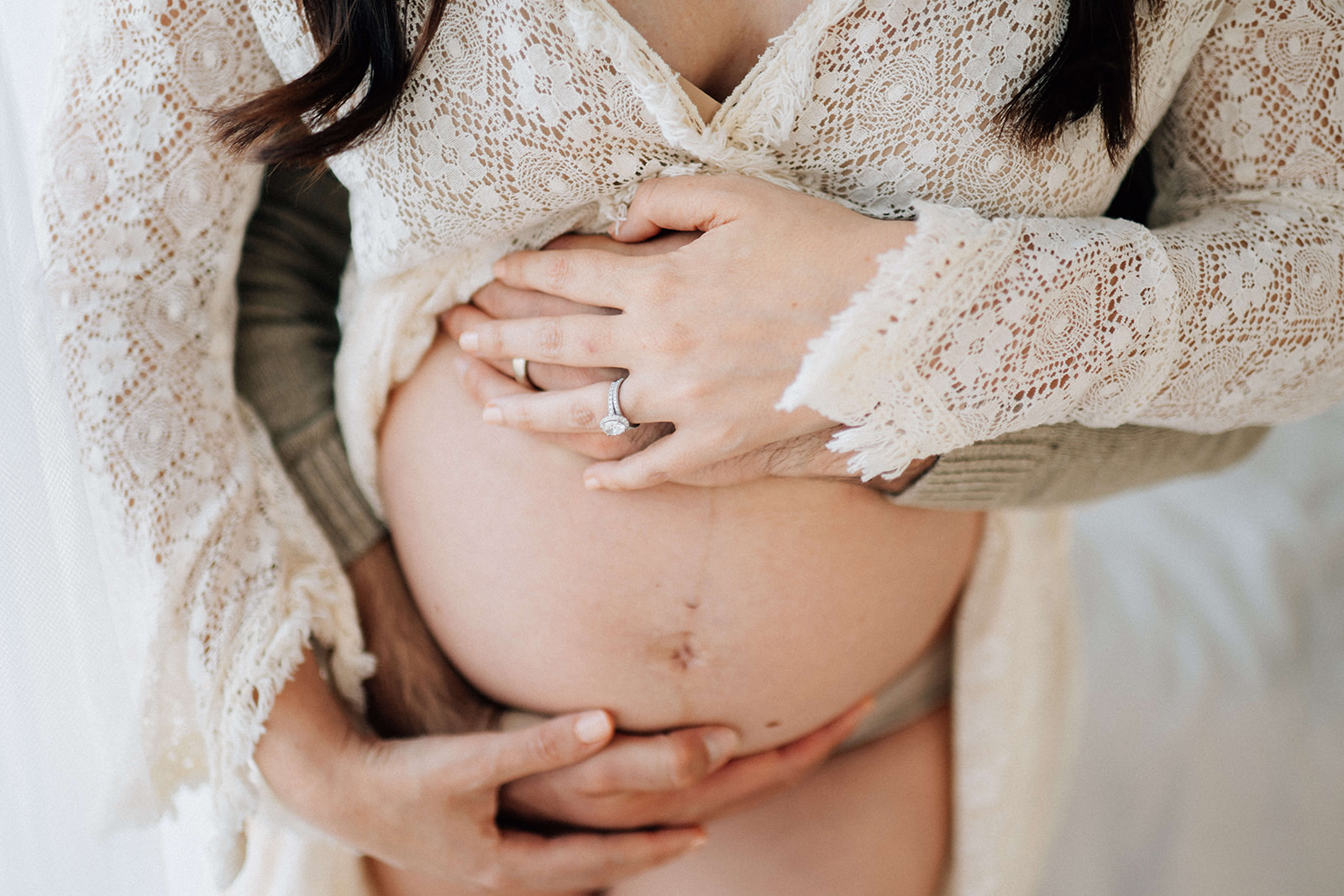 Details of an expecting snuggling with hands on the bump