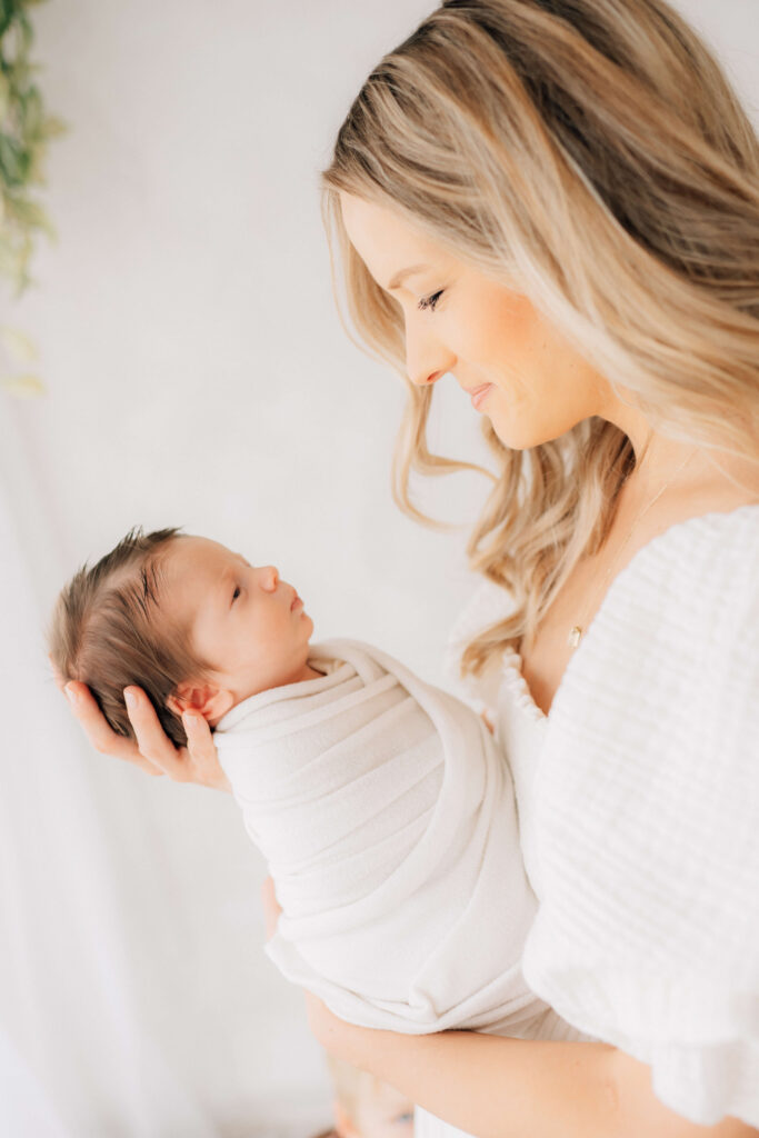side view of mom holding newborn and looking down toward him