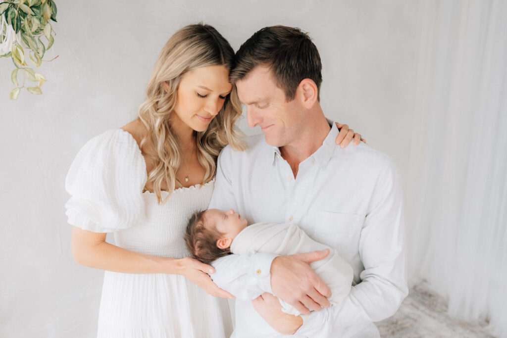 dad holding newborn baby while mom leans in with a good Denver photographer  